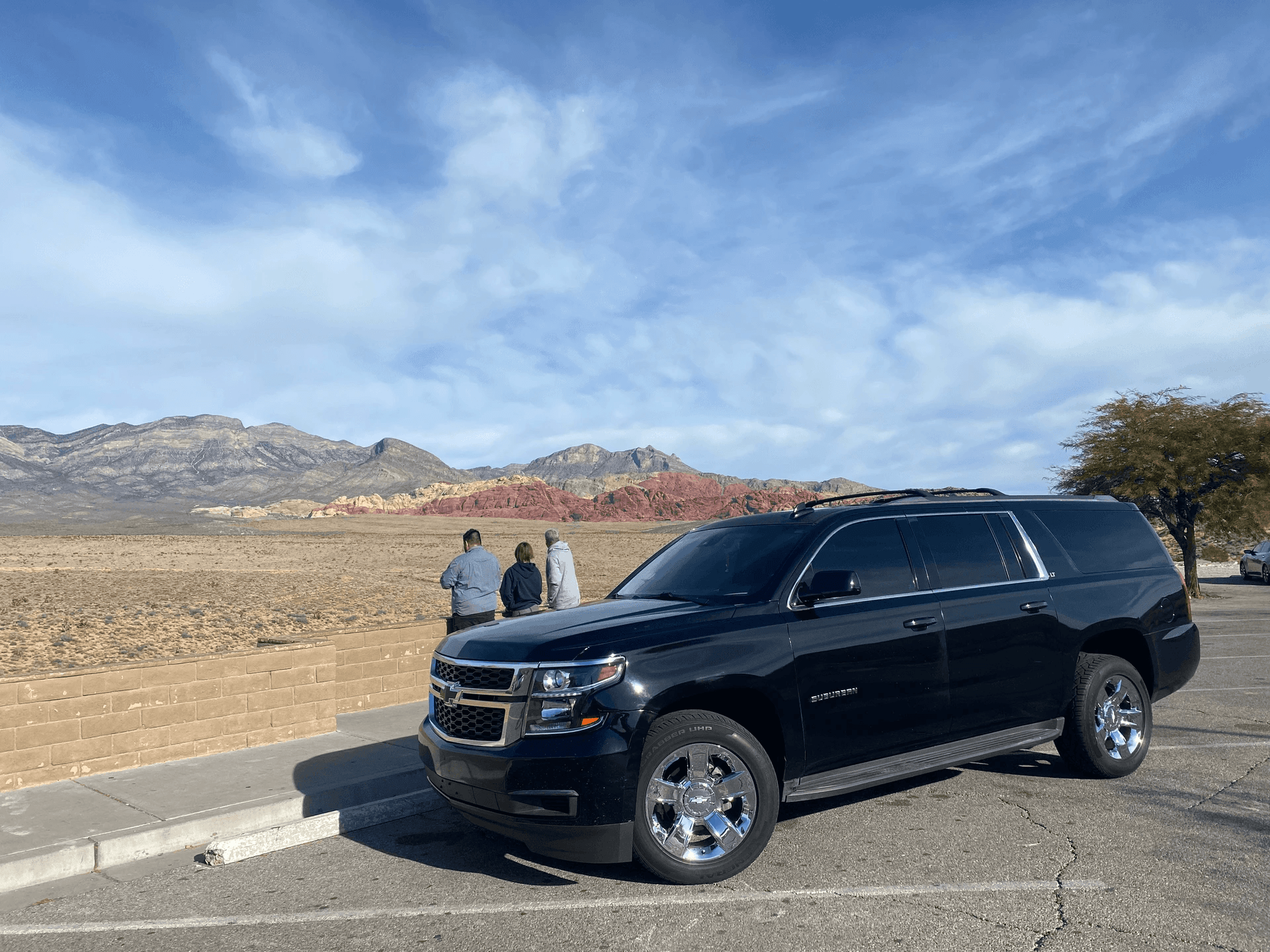 Black SUV parked at scenic overlook with distant mountain views
