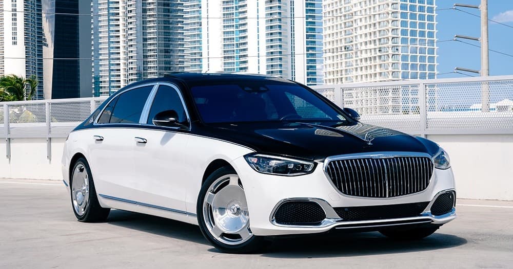 White luxury sedan on rooftop against modern city skyline