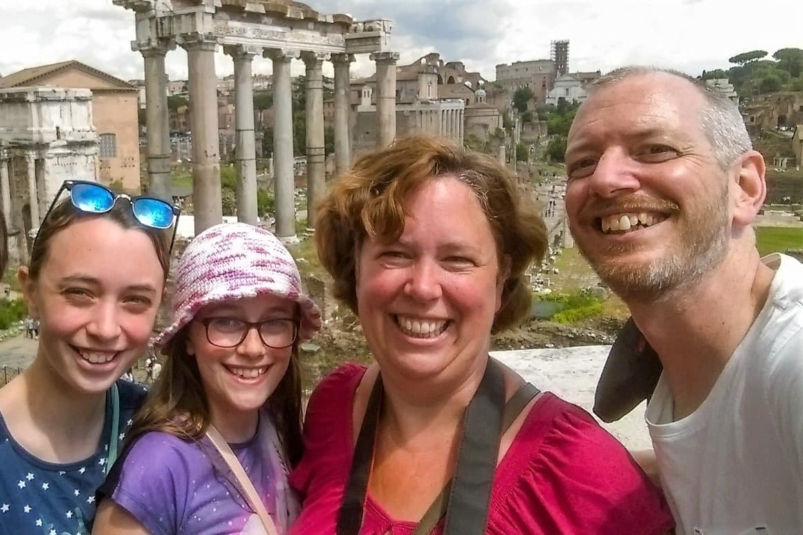 Smiling family with Roman Forum ruins and ancient temple columns in Rome