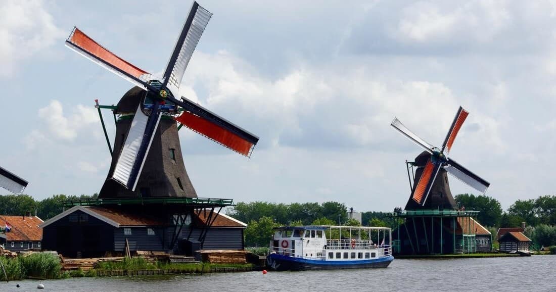 Historic Dutch windmills beside canal with Alkmaar cruise boat