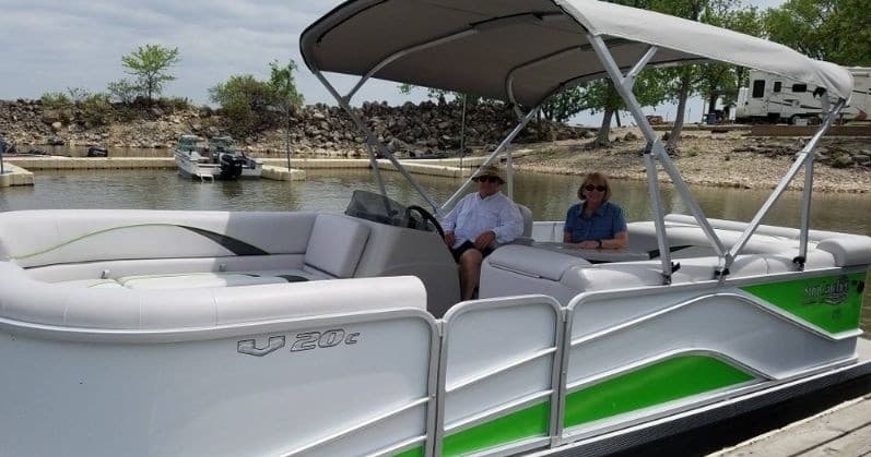 Pontoon boat docked at marina with passengers preparing to cruise