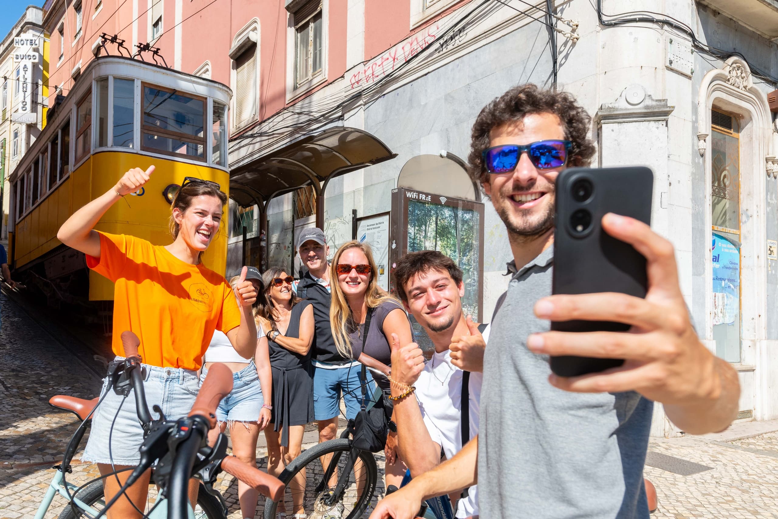 Friends taking cycling selfie on Lisbon tram-lined street tour