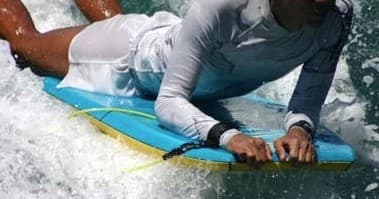 Bodyboarder riding whitewater wave off coastal shore