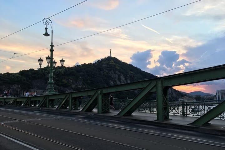 Sunset walk across Liberty Bridge with river and city skyline view