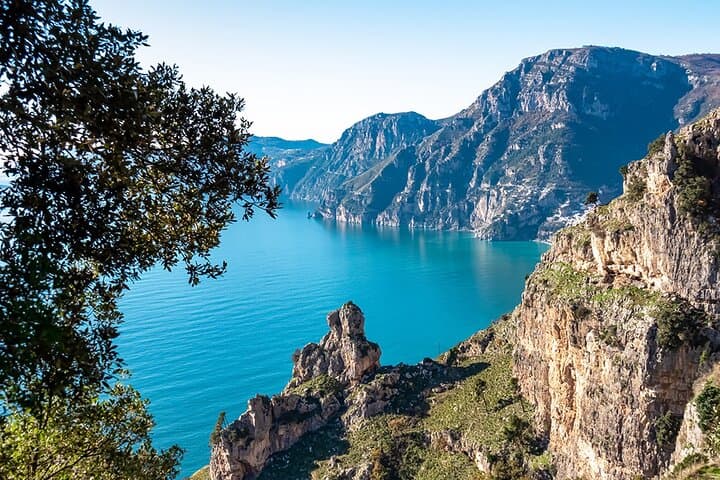 Turquoise coastal cove framed by cliffs and seaside trees