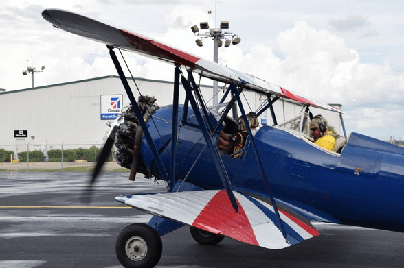 Parked vintage biplane on tarmac at small coastal airfield
