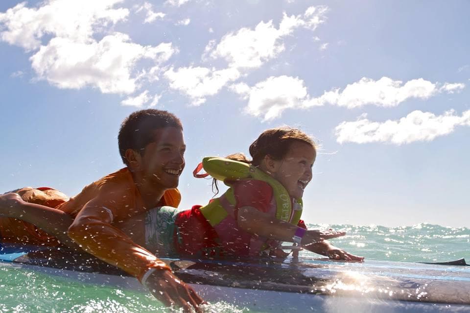 Father and child surfing together on a sunny reef break