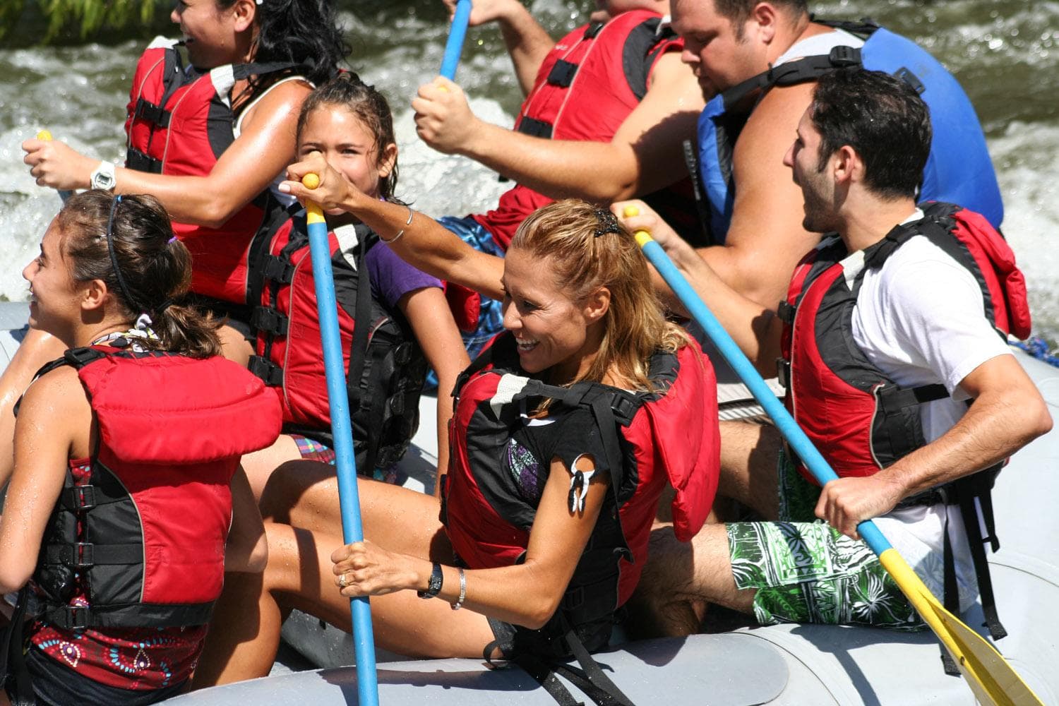 Large rafting group paddling together down lively river rapids