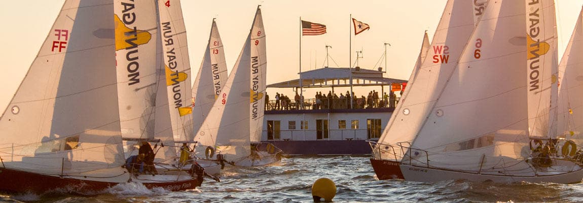 Sailboats racing near sunset with event dock and spectators