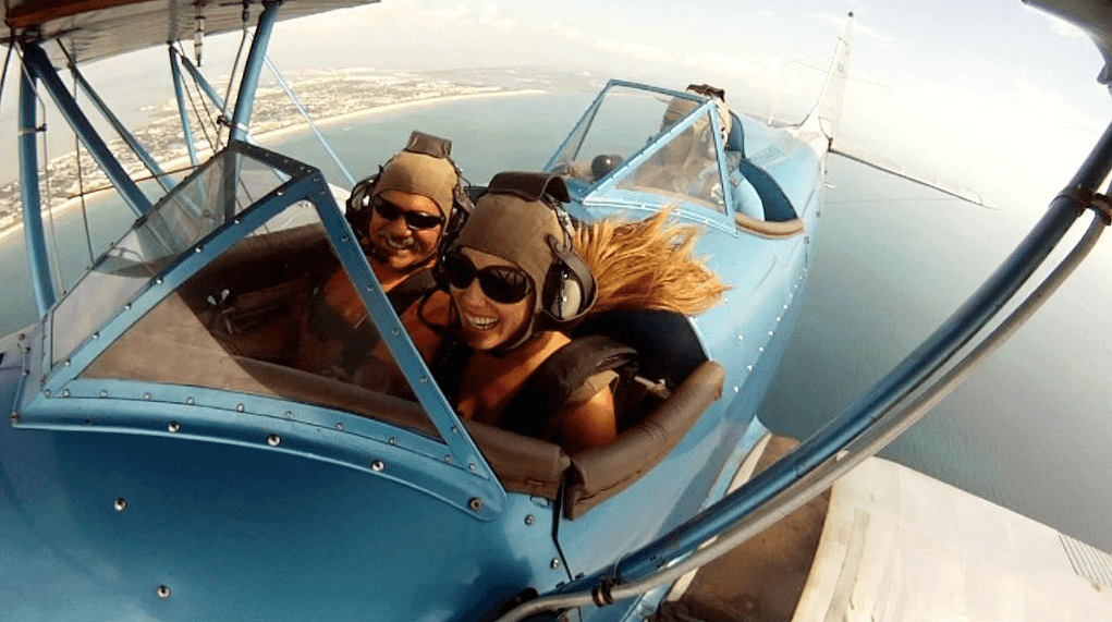 Passengers enjoying open-cockpit biplane sightseeing flight