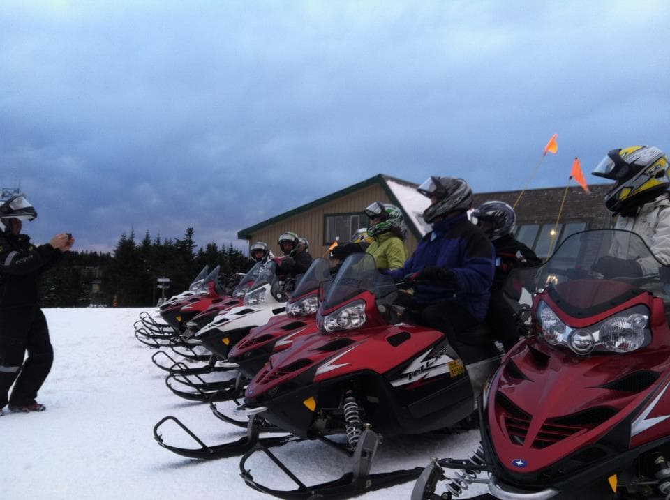 Lineup of snowmobiles parked on snowy lodge staging area