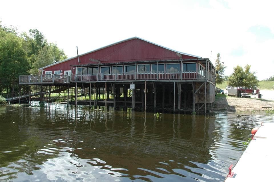 Riverside stilted boathouse over water on Louisiana bayou dock