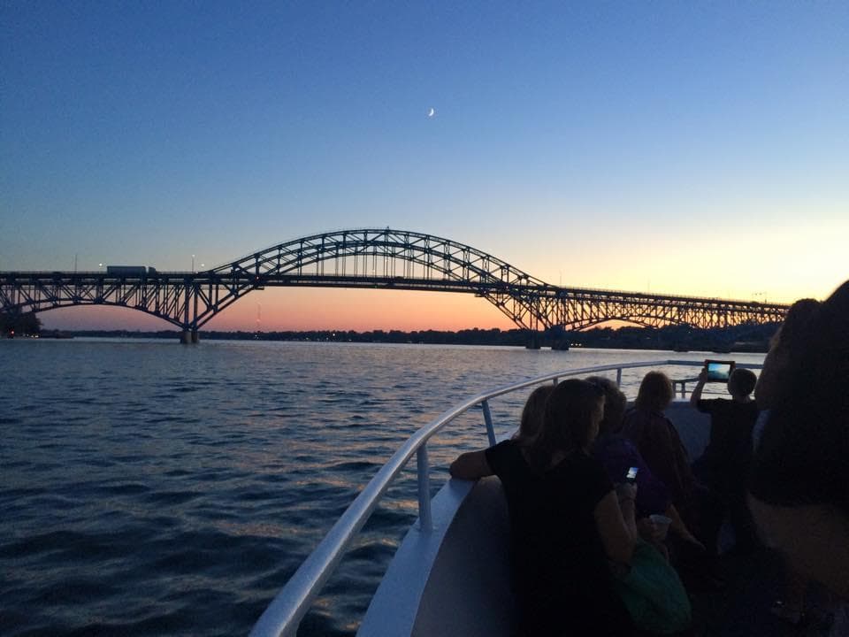 Sunset harbor cruise passing arched bridge with passengers aboard