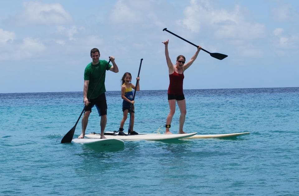 Family stand-up paddleboarding together on turquoise ocean