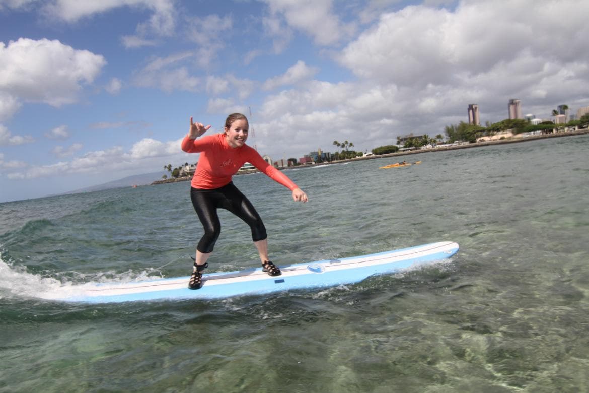 Surfer riding shallow reef with shoreline backdrop, tropical surf