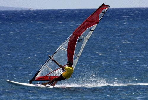 Speeding windsurfer planing across deep blue open ocean