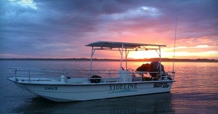 Tour boat silhouetted at sunset over tranquil harbor waters