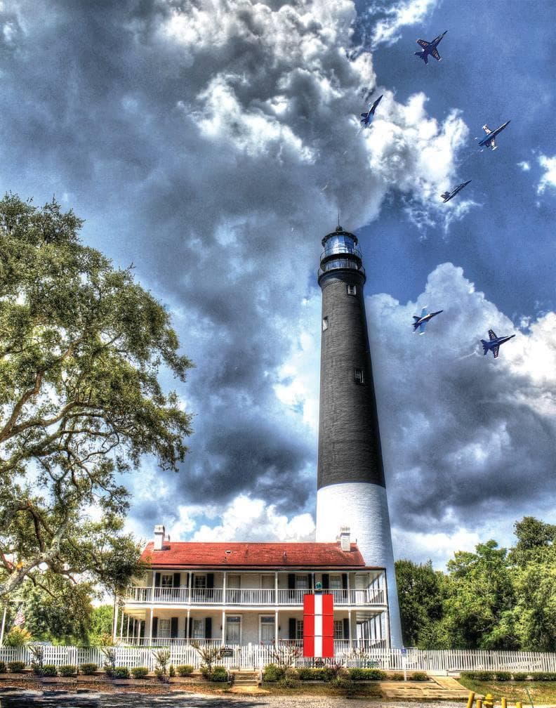 Pensacola Lighthouse rising with dramatic clouds and flyover
