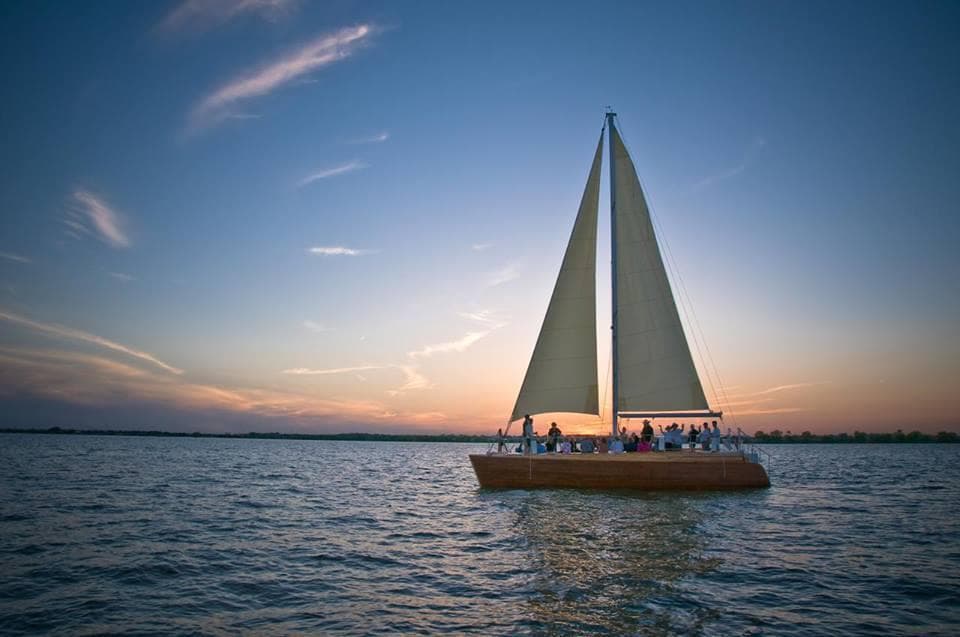 Sailboat cruising at sunset on open water with dramatic sky