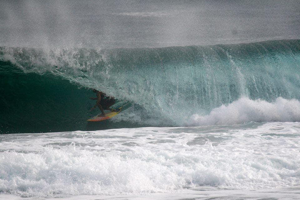 Surfer riding inside a hollow reef barrel wave near Kona shore