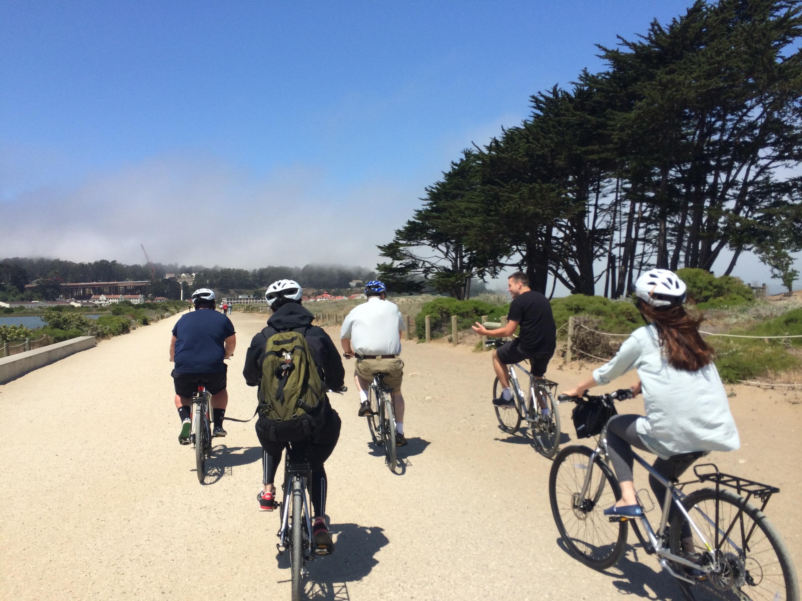 Group cycling along coastal trail near San Francisco shore