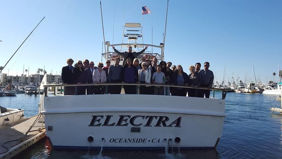 Charter sportfishing crew posing on stern of Electra in marina