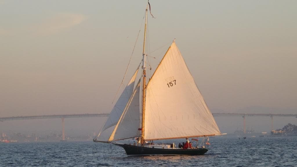 Classic sailboat at sunset gliding across calm bay waters