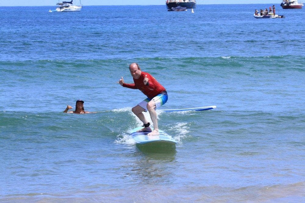 Surfer riding small breakline waves in clear blue ocean