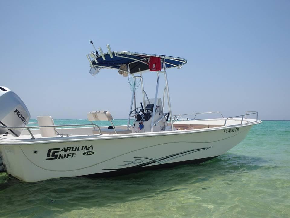 Center console boat anchored in shallow turquoise coastal water