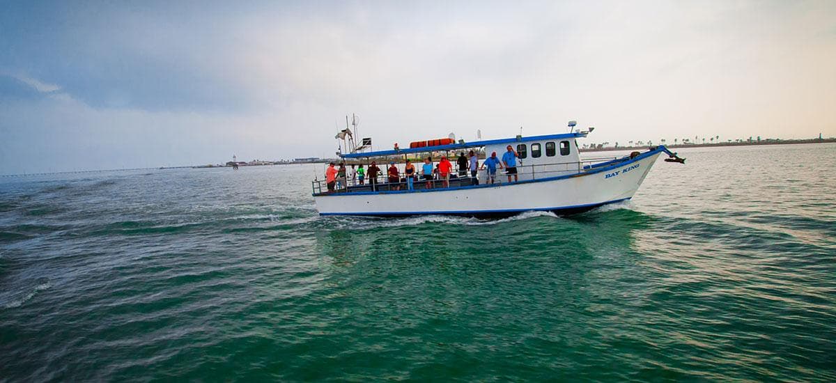 Passenger sightseeing boat cruising on open coastal waters at sunset