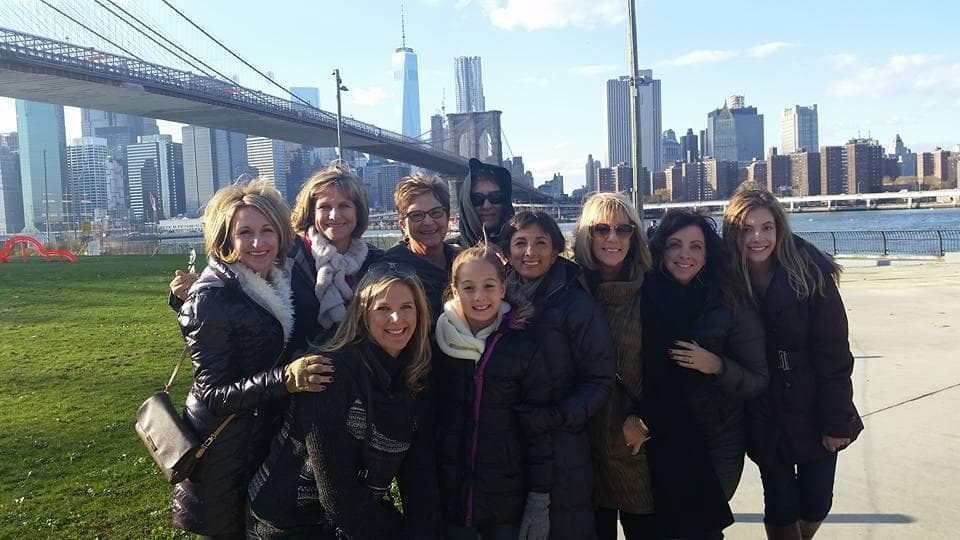 Group posing by Brooklyn Bridge with Manhattan skyline backdrop