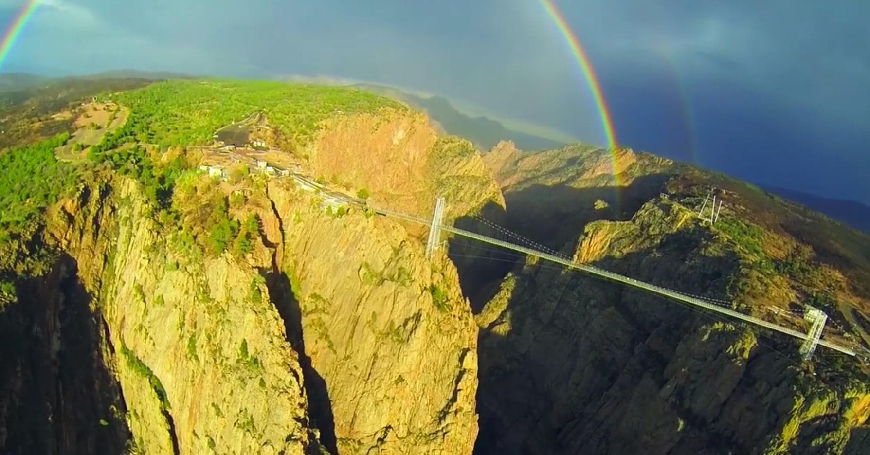Aerial helicopter tour above canyon with vivid rainbow arc