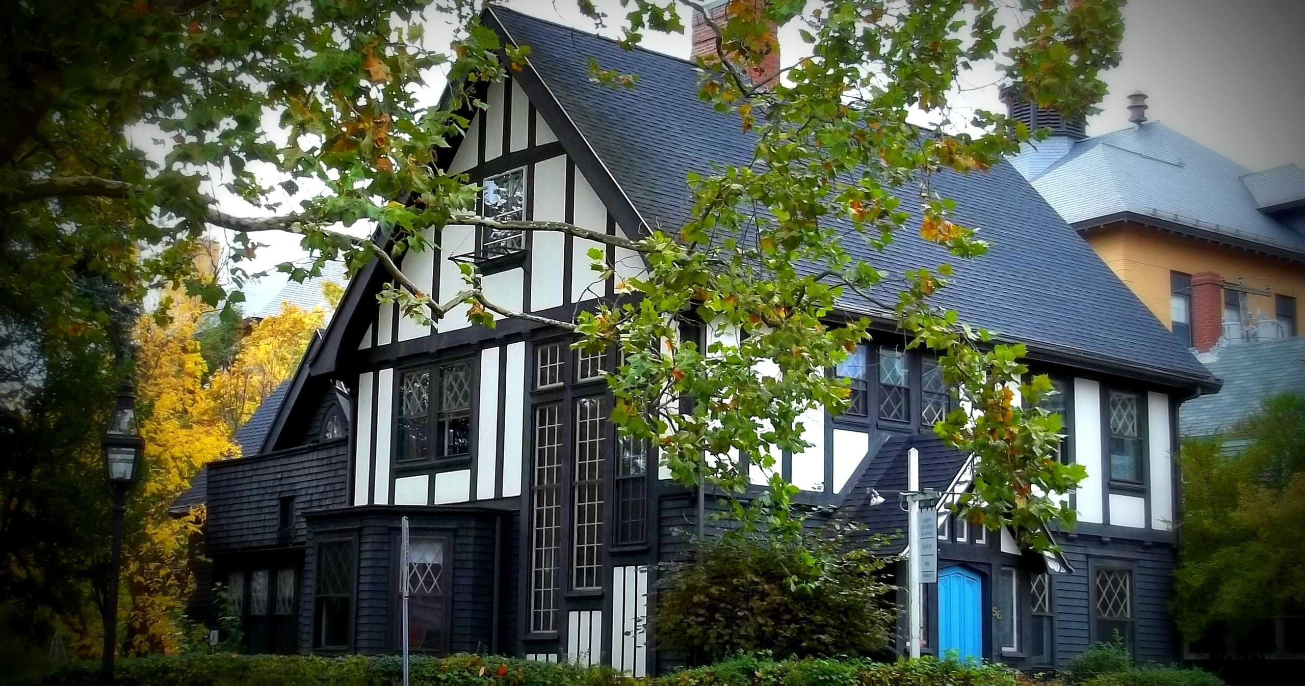 Historic Tudor-style seaside house amid fall foliage in New England