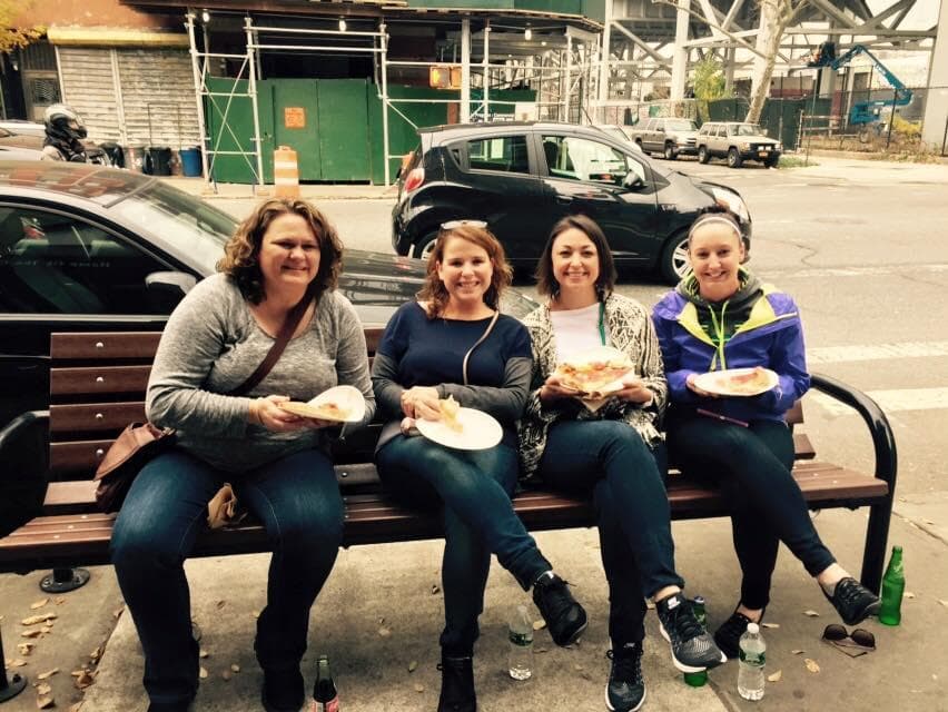 Friends eating on bench during outdoor Brooklyn walking tour