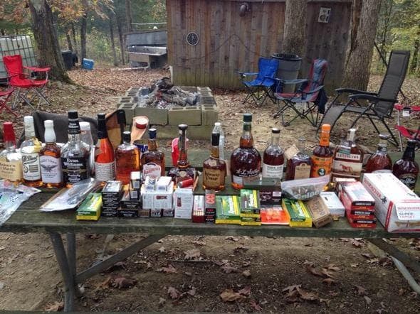 Outdoor bourbon tasting setup on picnic table at camp site