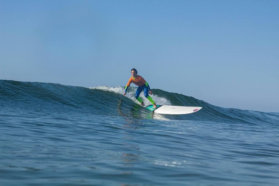 Surfer riding a clean blue ocean wave near sunny coastline