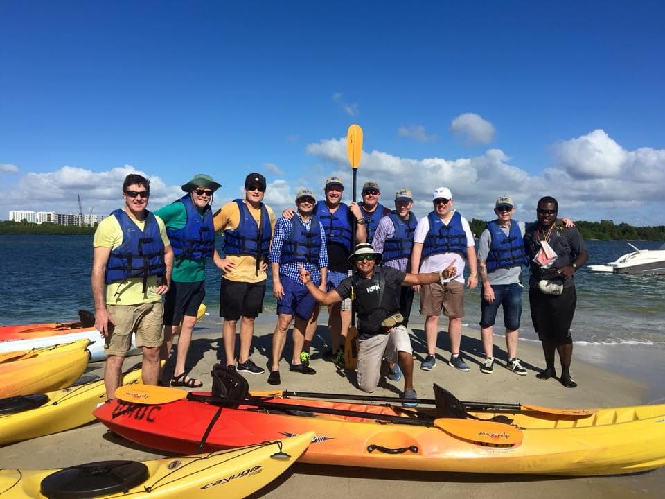Group of kayakers on sandy shore preparing for guided sea tour