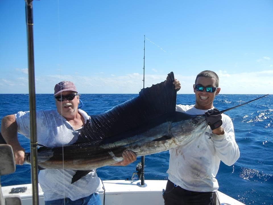 Anglers holding large sailfish on deep blue ocean fishing trip