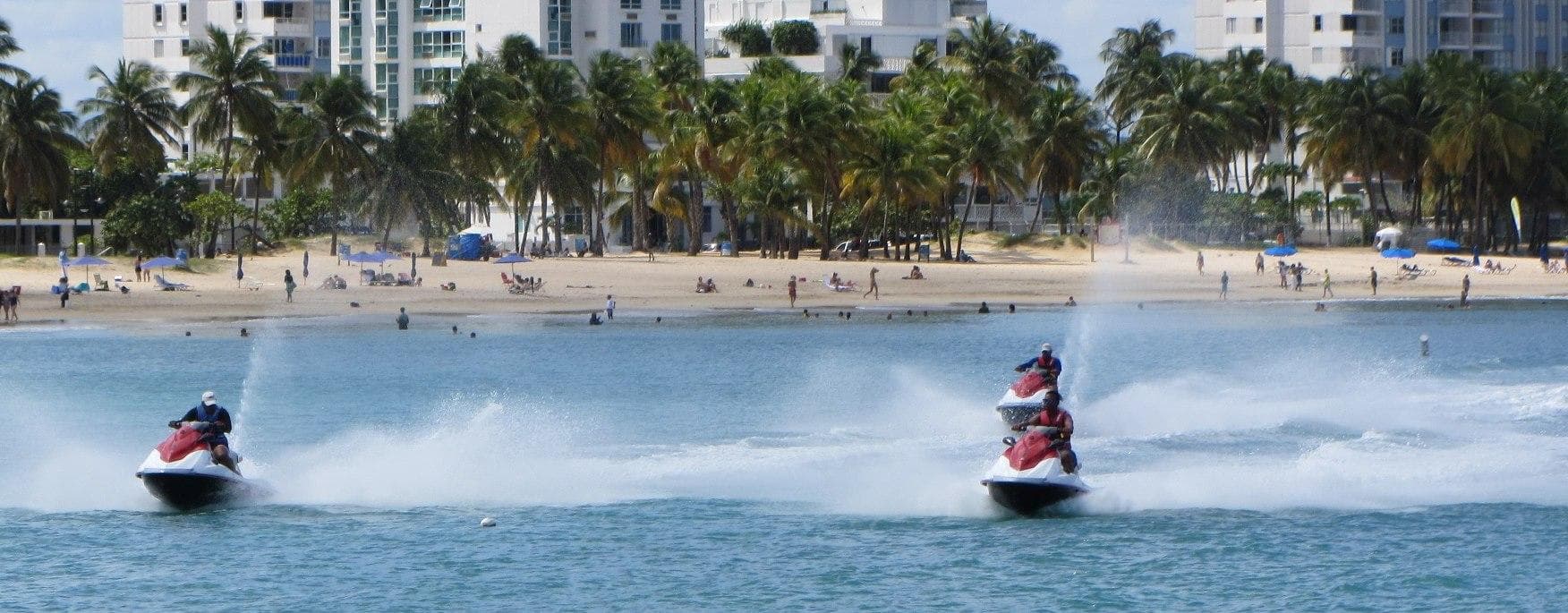 Two jet skis racing across tropical shoreline, high-speed ocean action