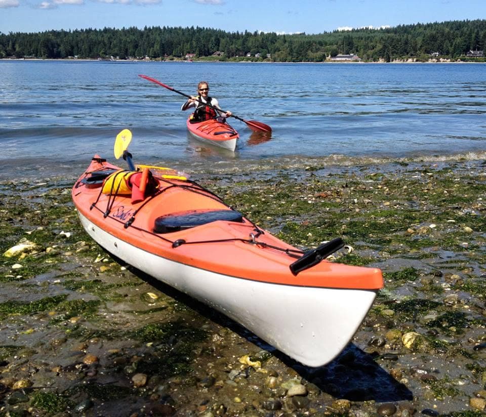 Single sea kayak beached on rocky shoreline ready for launch