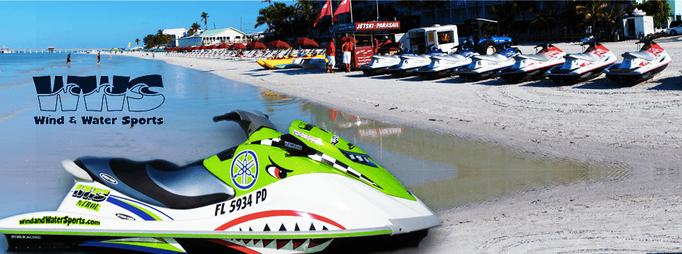 Jetski parked on sandy beach with ocean and equipment row