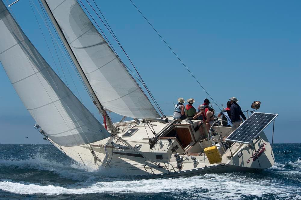 Crewed racing yacht heeling in choppy ocean during regatta
