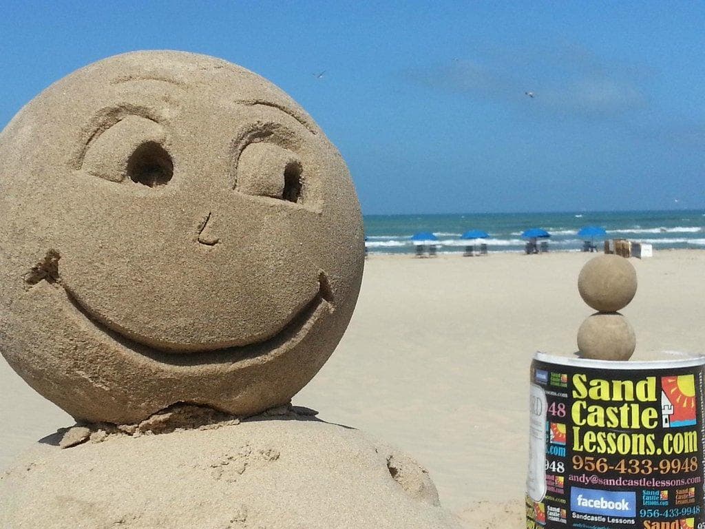 Smiling sand sculpture on sandy ocean beach shore