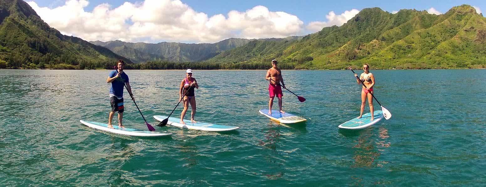 Stand-up paddleboarders cruising turquoise bay with mountain views