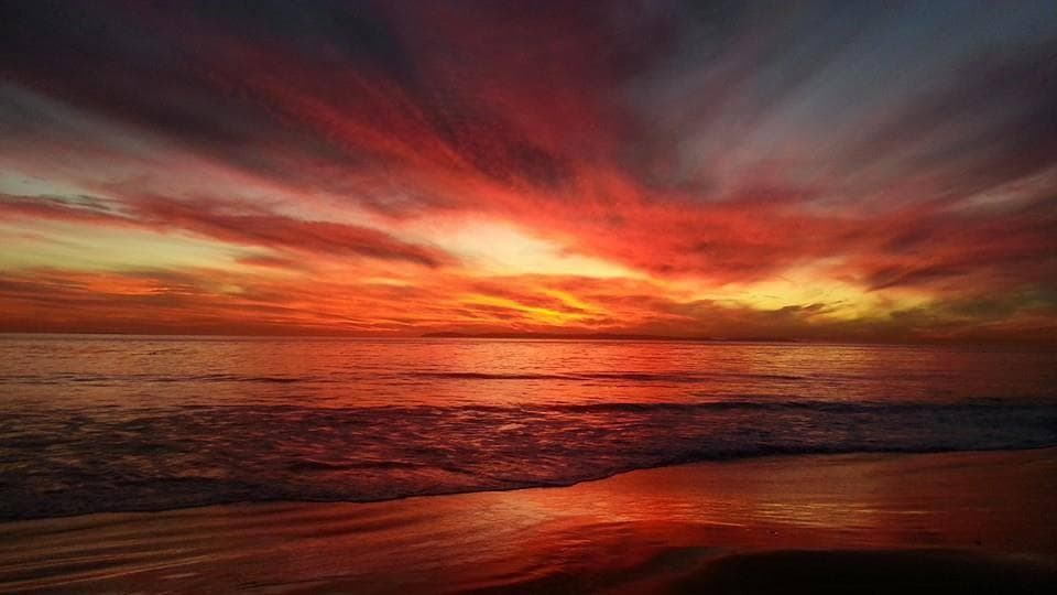 Vibrant sunset over Pacific beach, dramatic coastal shoreline