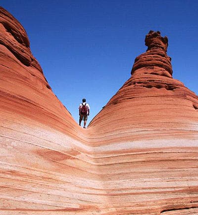 Hikers traversing Wave-like ridge, Vermilion Cliffs hiking adventure