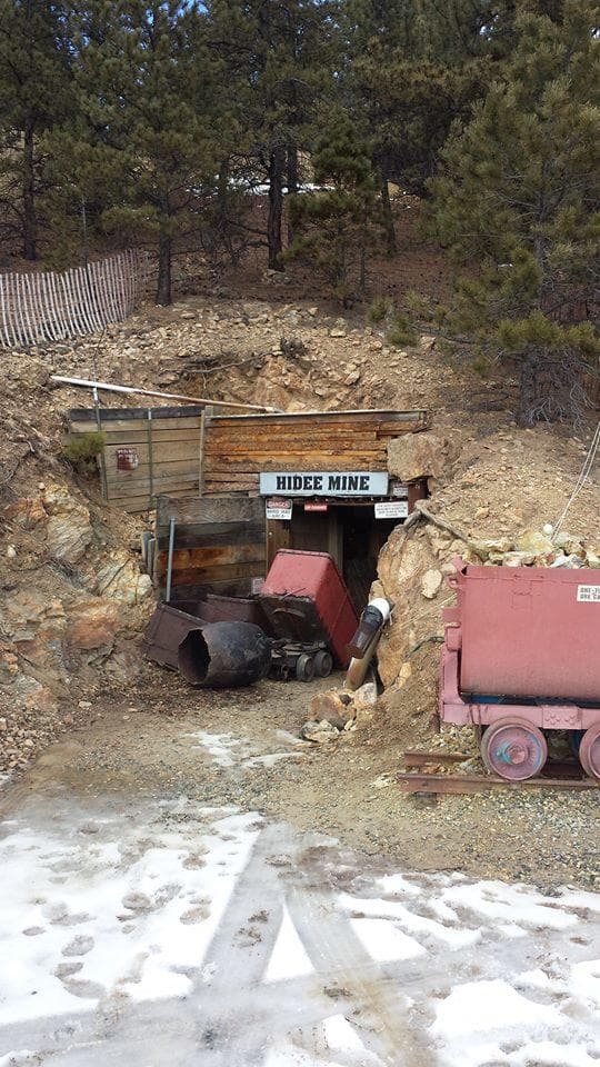 Snowy mine adit entrance with mining equipment at hillside site