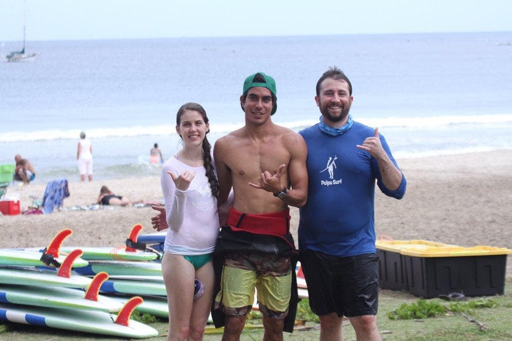 Surf instructors and students on sunny beach next to boards