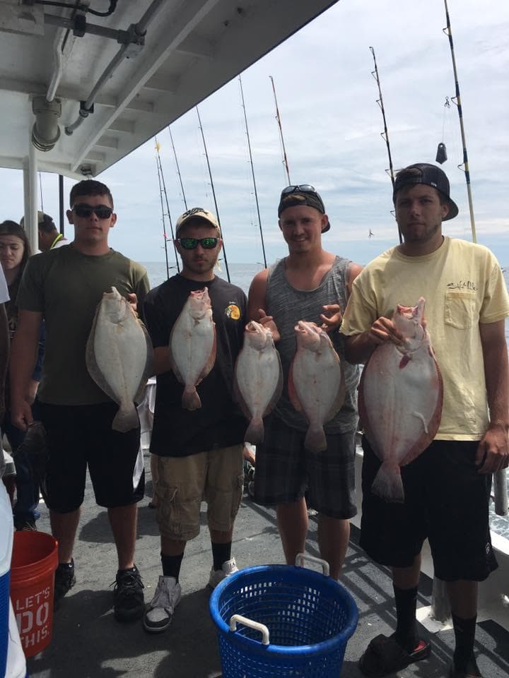 Group of anglers holding flounder aboard offshore fishing charter
