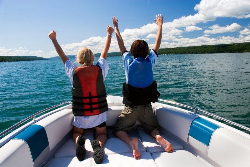 Children celebrating on a bow of a speedboat on blue lake